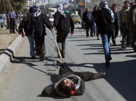 Arabs drag the body of a suspected collaborator along a street in Hebron